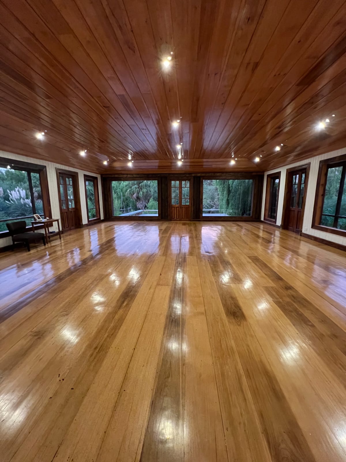 Estudio — salón de piso de madera y ventanales al Delta